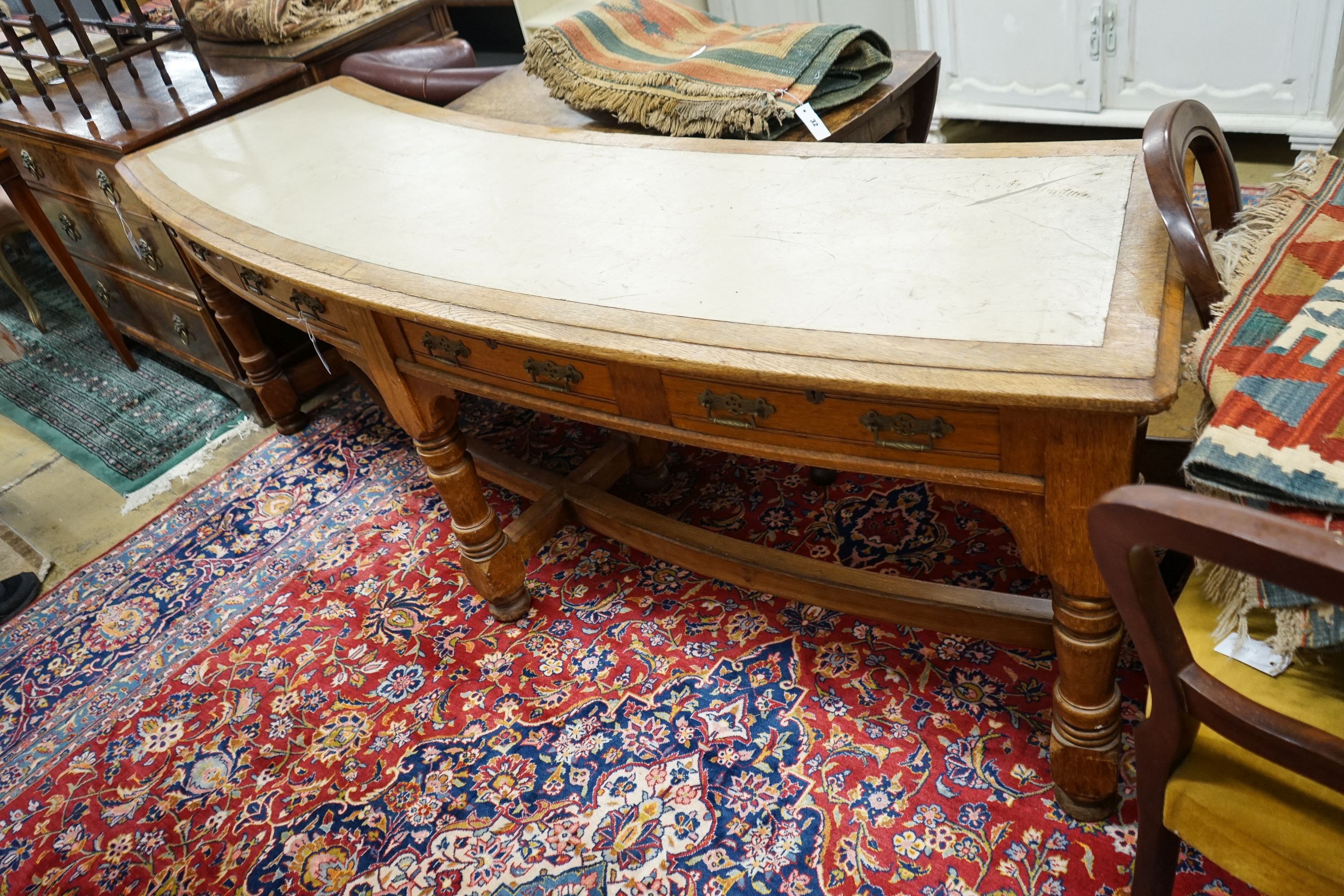 A late Victorian oak four drawer library table of curved rectangular form, length 240cm, depth 60cm, height 80cm